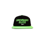 The Reebok Ordinary Elite Cap features a black design with a bright green flat brim, bold green "ORDINARY ELITE" embroidery on the front, a small white logo beneath, and an adjustable snapback closure for comfort.
