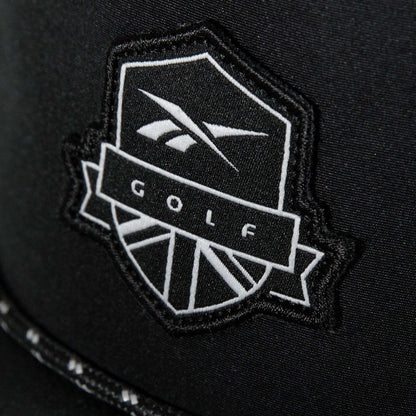 A close-up of the Madison Ii by Reebok shows a black patch with a white shield and stylized logo reading "GOLF" in bold, featured on a recycled polyester hat with an adjustable snapback.
