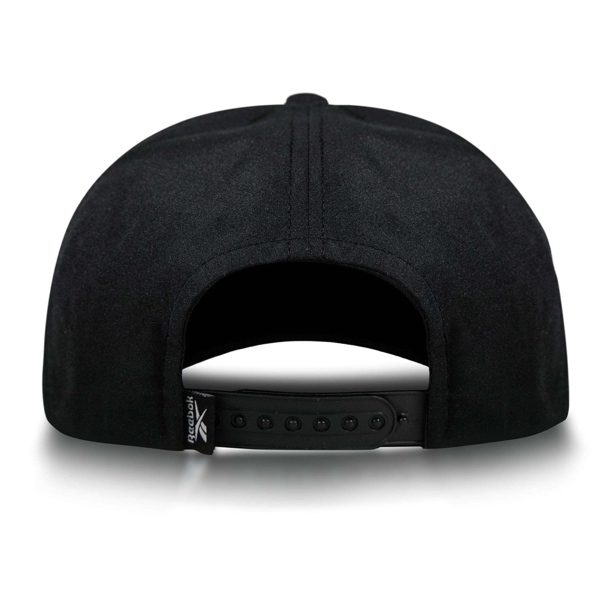 The Reebok Madison Ii is a black recycled polyester hat with an adjustable snapback closure and a small folded tag featuring the Reebok logo on the left side, viewed from the back.