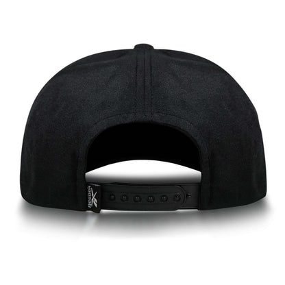 The Reebok Madison Ii is a black recycled polyester hat with an adjustable snapback closure and a small folded tag featuring the Reebok logo on the left side, viewed from the back.