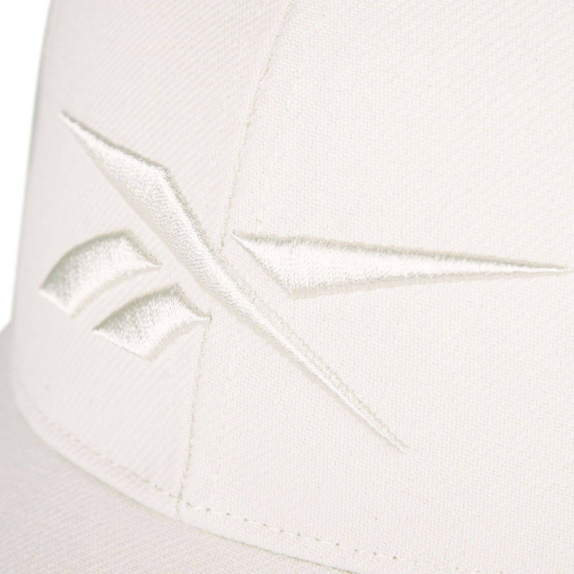 Close-up of the Vector Baseball Cap by Reebok, crafted in off-white fabric and detailed with a matching embroidered Reebok logo.