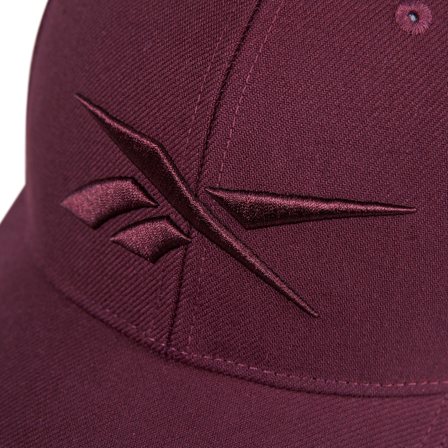 Close-up of the Reebok Vector Baseball Cap in maroon, featuring a maroon embroidered Reebok logo on the front.