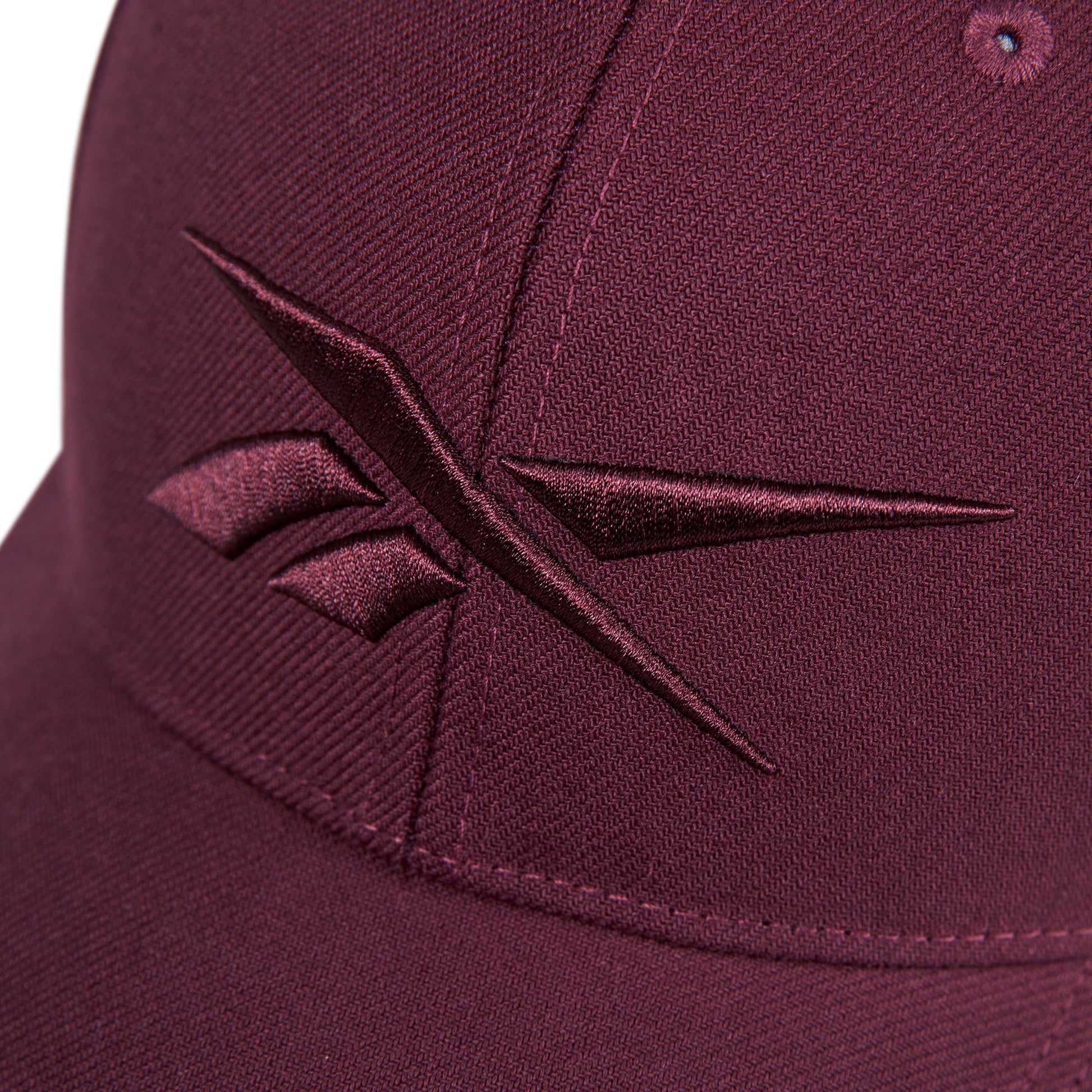 Close-up of the Reebok Vector Baseball Cap in maroon, featuring a maroon embroidered Reebok logo on the front.
