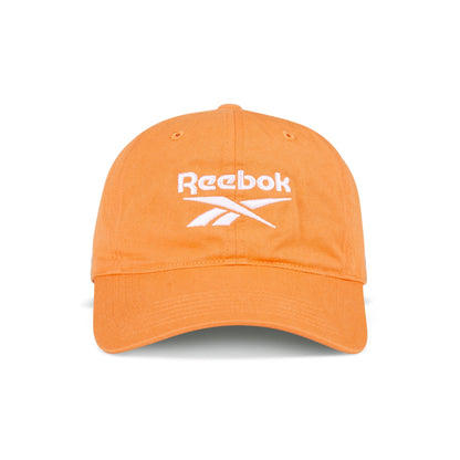 The Reebok Logo Cap features bright orange cotton twill, a curved brim, and a white embroidered logo on the front. It has an adjustable buckle closure for a custom fit and is shown against a white background.