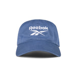 The Reebok Logo Cap features a curved brim and front white logo embroidery. Made from cotton twill with an adjustable buckle for comfort, this cap is shown against a white background.