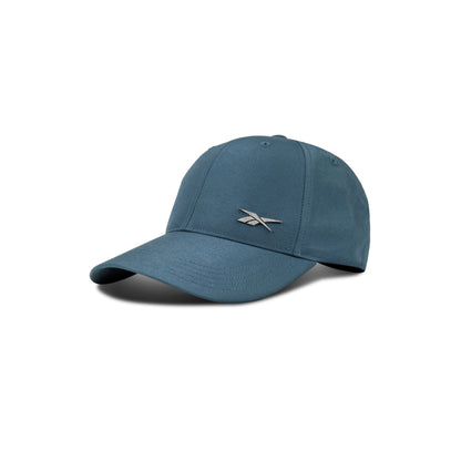 The Reebok Badge Cap is a blue adjustable sports hat with a curved brim and silver logo on the front, displayed on a white background with a shadow.
