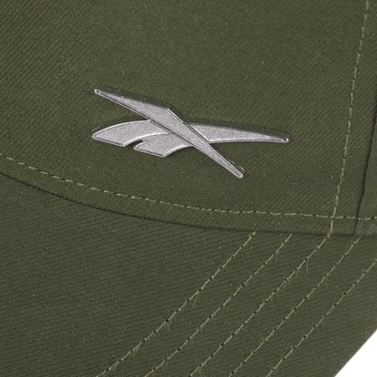Close-up of the silver Reebok logo on olive green fabric of the Reebok Badge Cap, featuring visible stitching and intersecting seams.