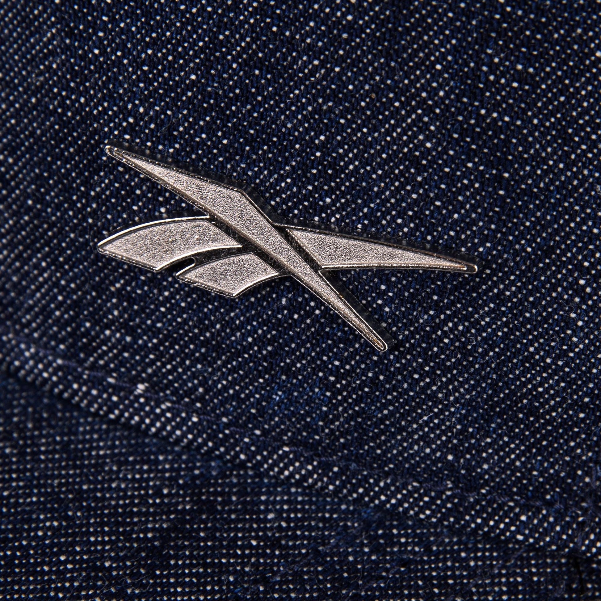 A metallic Reebok logo pin accents the textured blue Denim Badge Cap by Reebok, giving it a stylish edge.
