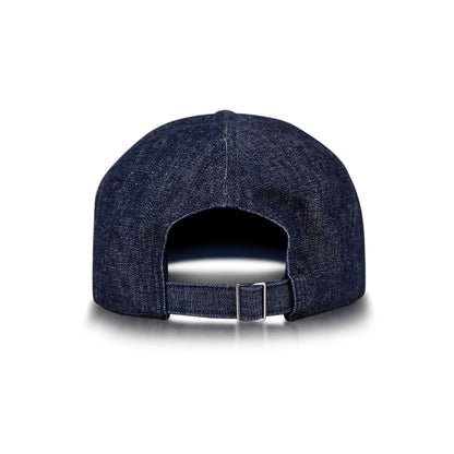 The Reebok Denim Badge Cap is shown from the back with an adjustable strap, metal buckle, and Speedwick sweatband. This dark blue cap appears on a white background with a subtle shadow beneath it.
