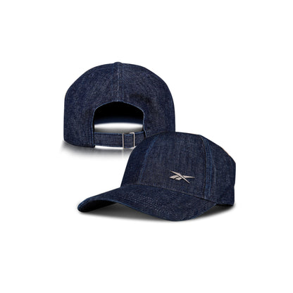 Two Denim Badge Caps by Reebok are shown on a white background: one displays the front with a small white Reebok logo, the other shows the back and adjustable strap. Both include a Speedwick sweatband for comfort.