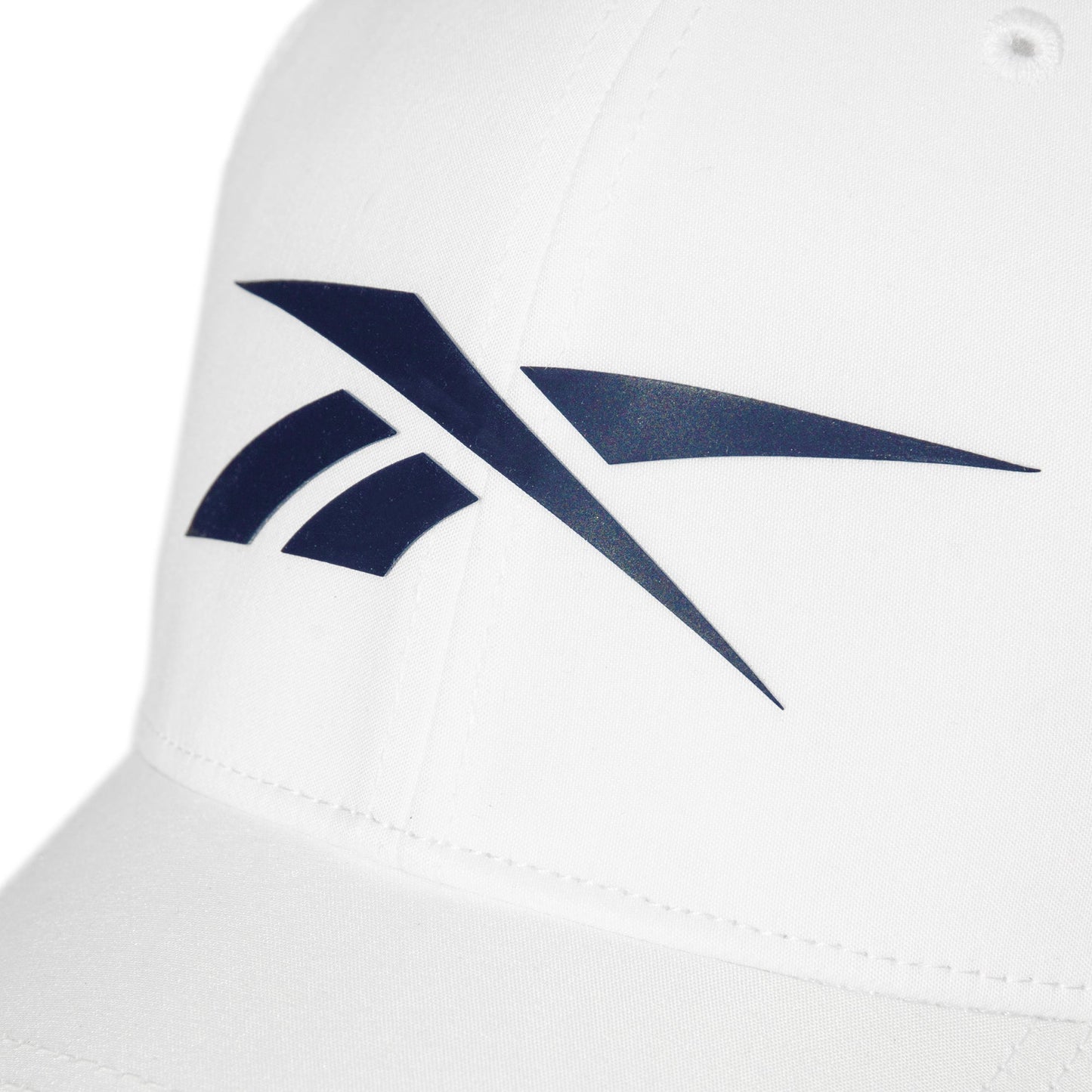 Close-up of a white Reebok Elite Cap, a fitted performance hat with a prominent dark blue Reebok logo on the front.