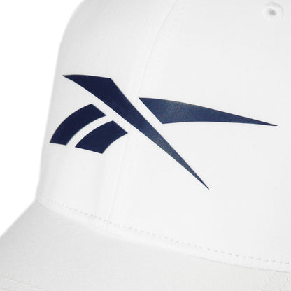 Close-up of a white Reebok Elite Cap, a fitted performance hat with a prominent dark blue Reebok logo on the front.