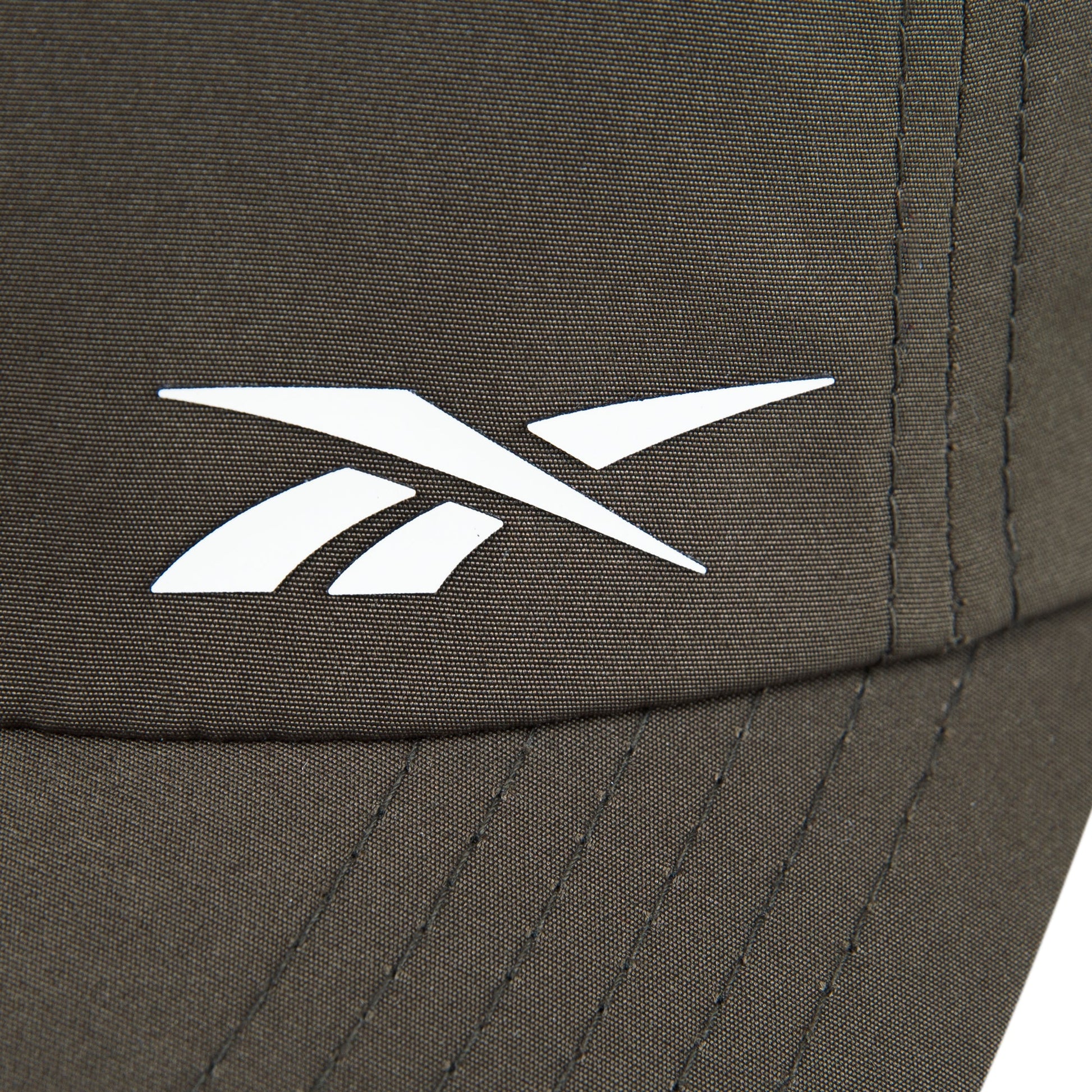 Close-up of the Reebok Flow Cap in brown, crafted from recycled polyester with a white Reebok logo, visible stitching, and a moisture-wicking sweatband for comfort.