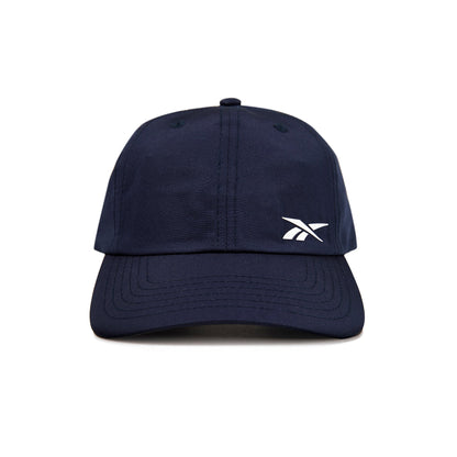 A front view of the Reebok Flow Cap in navy blue, featuring a small white Reebok logo on the left crown and a moisture-wicking sweatband for comfort.