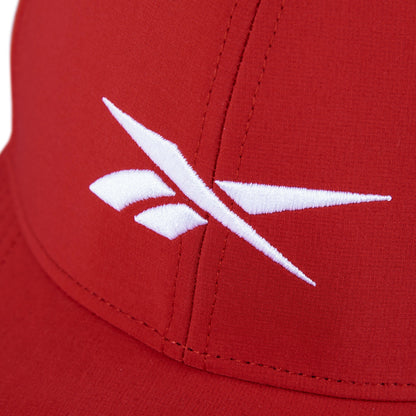Close-up of the Reebok Range Cap, a red golf hat with a white embroidered logo of angled lines and shapes on the front panel, offering sun protection and moisture-wicking comfort.