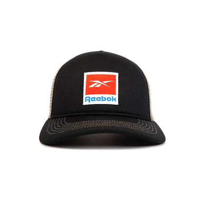 The Reebok Vintage Trucker Cap is black with white stitching, mesh back, a red and white Reebok logo patch on the front, and an adjustable snapback closure for classic athletic heritage style.