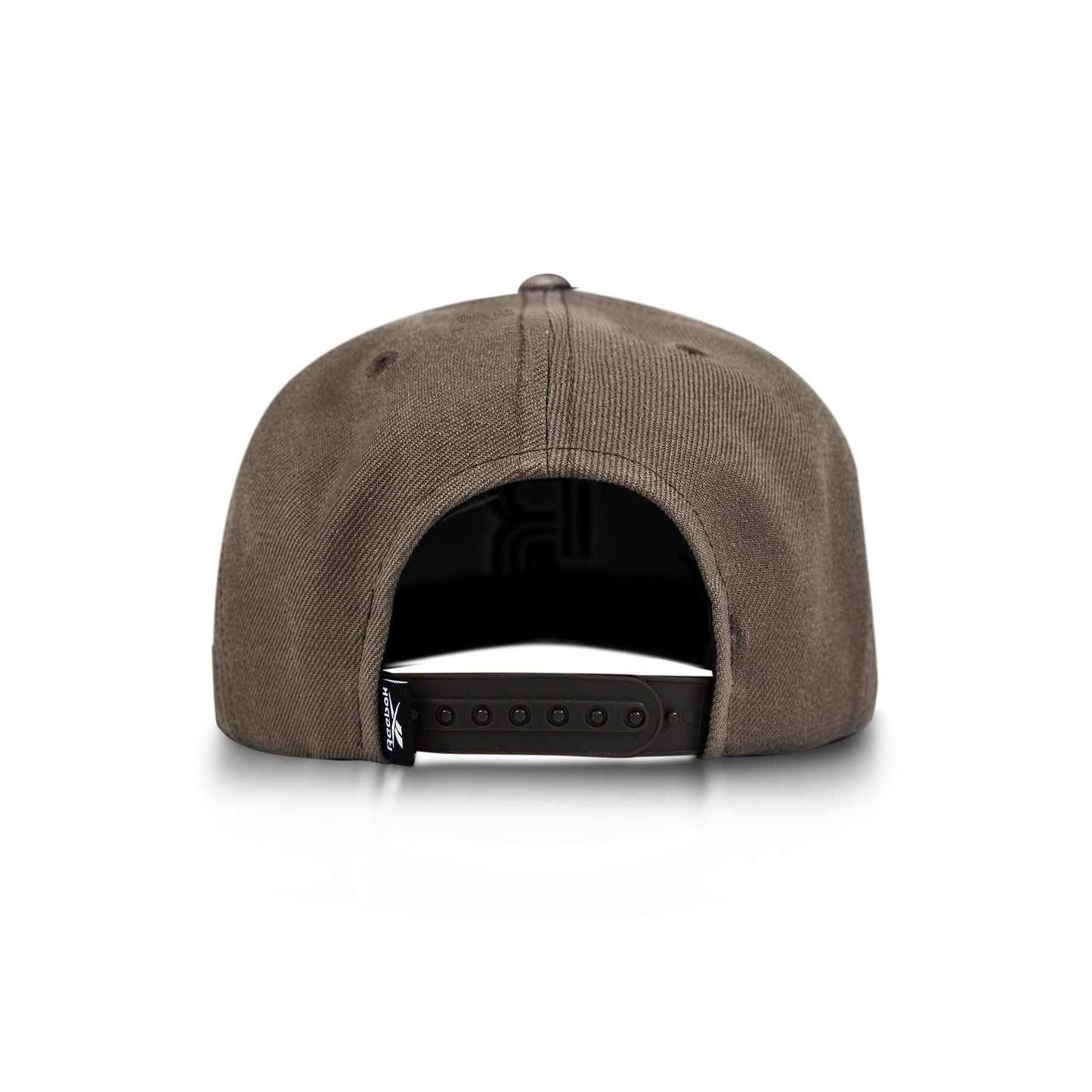 A brown Reebok Identity Drop R Cap is shown from the back on a white background, highlighting its adjustable snapback closure and a small black tag on the left side.