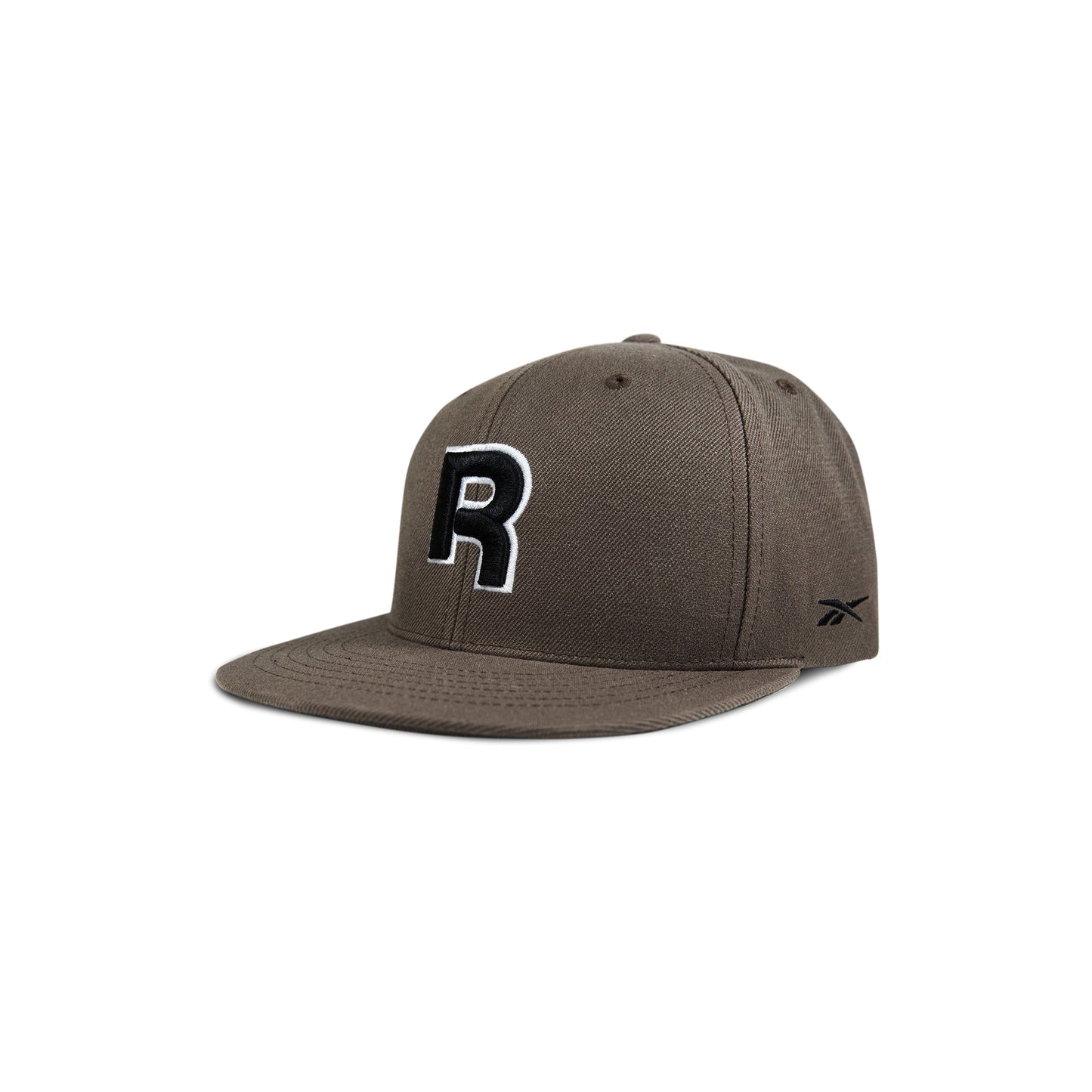The Reebok Identity Drop R Cap features a flat brim, large black and white R on the front, small side logo, and a snapback closure. Shown in brown on a white background.