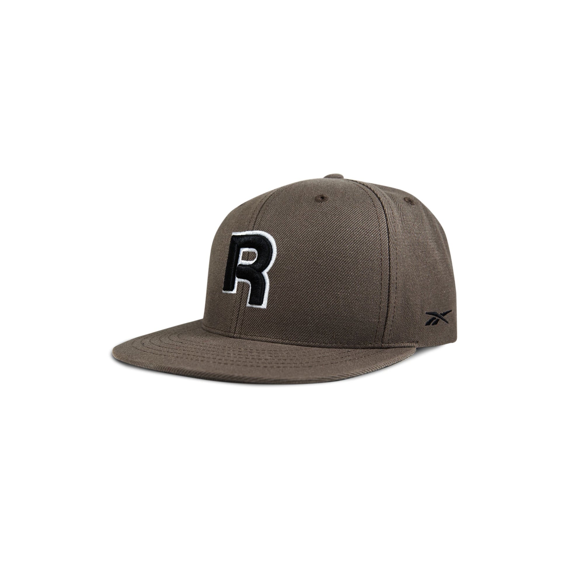 The Reebok Identity Drop R Cap features a flat brim, large black and white R on the front, small side logo, and a snapback closure. Shown in brown on a white background.