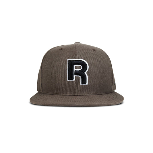 The Reebok Identity Drop R Cap is a brown flat-brim hat with a large black and white "R" embroidered on the front, snapback closure, and is shown against a plain white background.