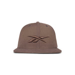 The Reebok Identity Vector Cap is a brown flat-brimmed hat with an embroidered Reebok logo on the front, displayed against a white background.