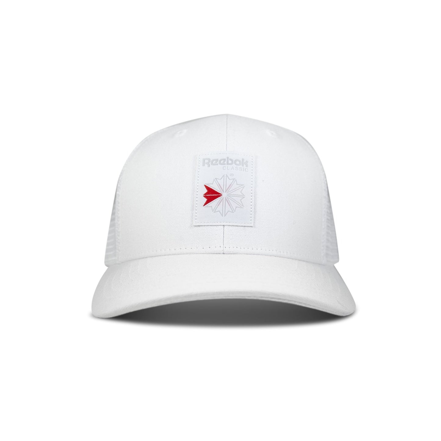 The Reebok Woven Patch Vector Trucker Cap is a white cap with mesh back panels and a rectangular patch on the front featuring the Reebok logo in gray with a red accent.