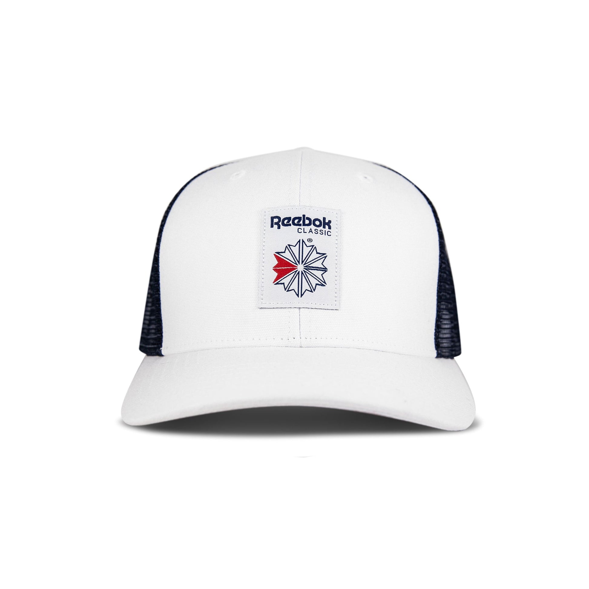 The Reebok Woven Patch Vector Trucker Cap is white with black mesh sides, a curved brim, and a navy/red logo patch. This adjustable snapback is shown on a plain white background.