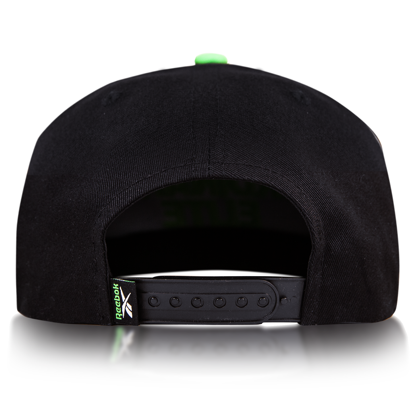 Rear view of the Reebok Ordinary Elite Cap, featuring a cotton crown, adjustable snapback plastic strap, and a small green Reebok logo tag on the left side. Shown against a plain white background.