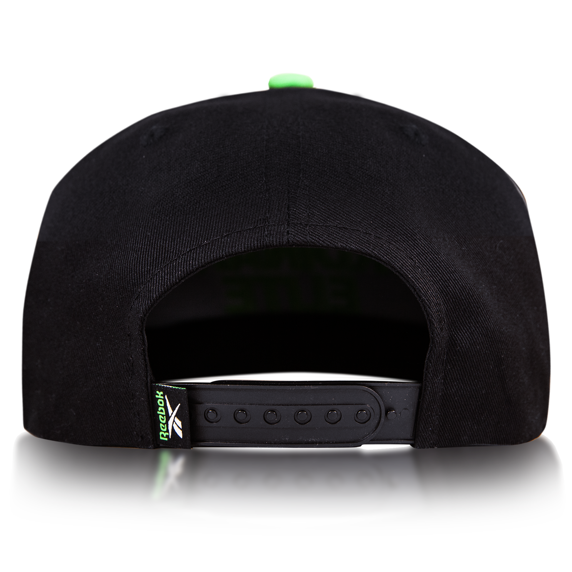 Rear view of the Reebok Ordinary Elite Cap, featuring a cotton crown, adjustable snapback plastic strap, and a small green Reebok logo tag on the left side. Shown against a plain white background.