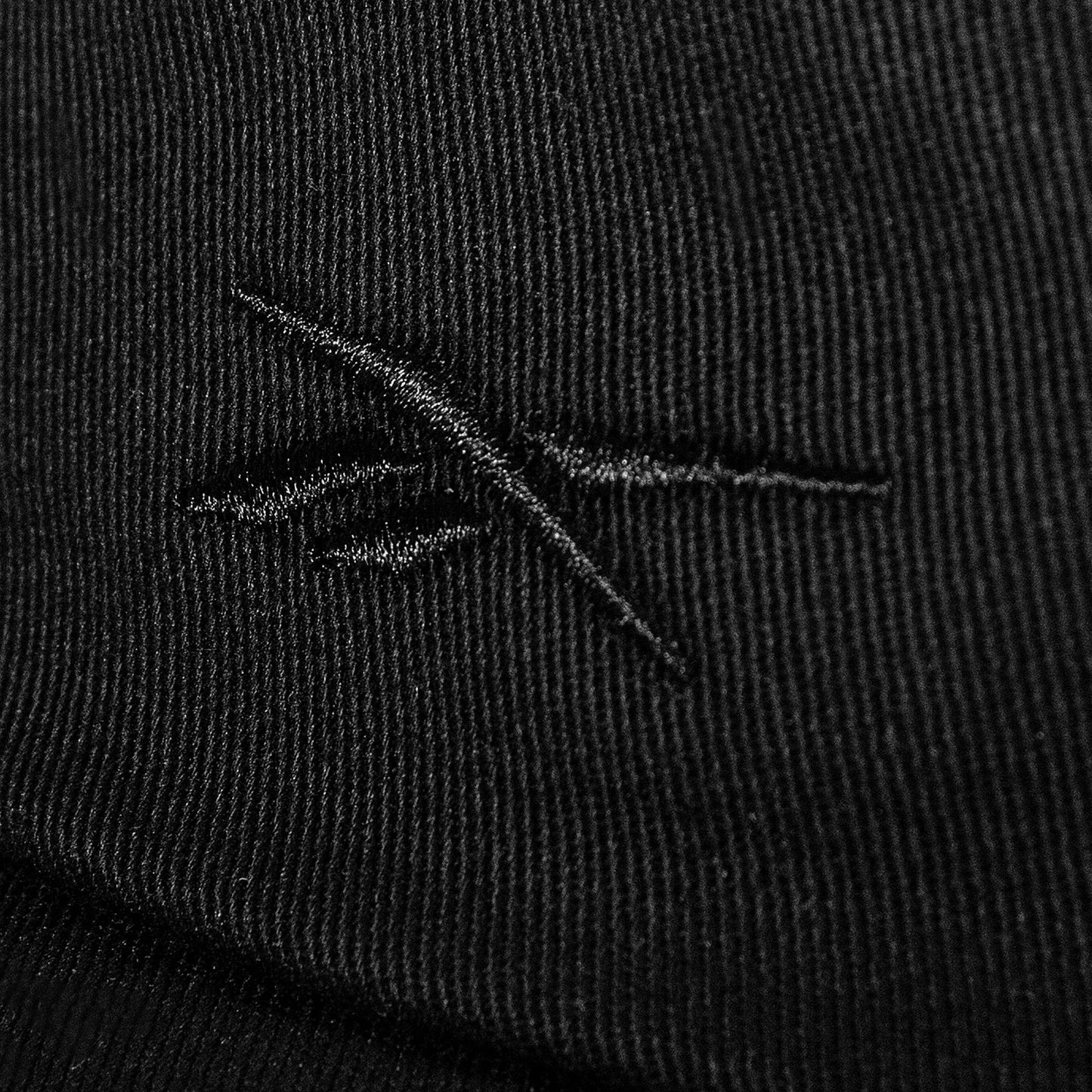Close-up of black cotton twill fabric on the Reebok Logo S-Vector Cap, featuring a stitched abstract crossed-lines logo and textured pattern on an adjustable snapback.