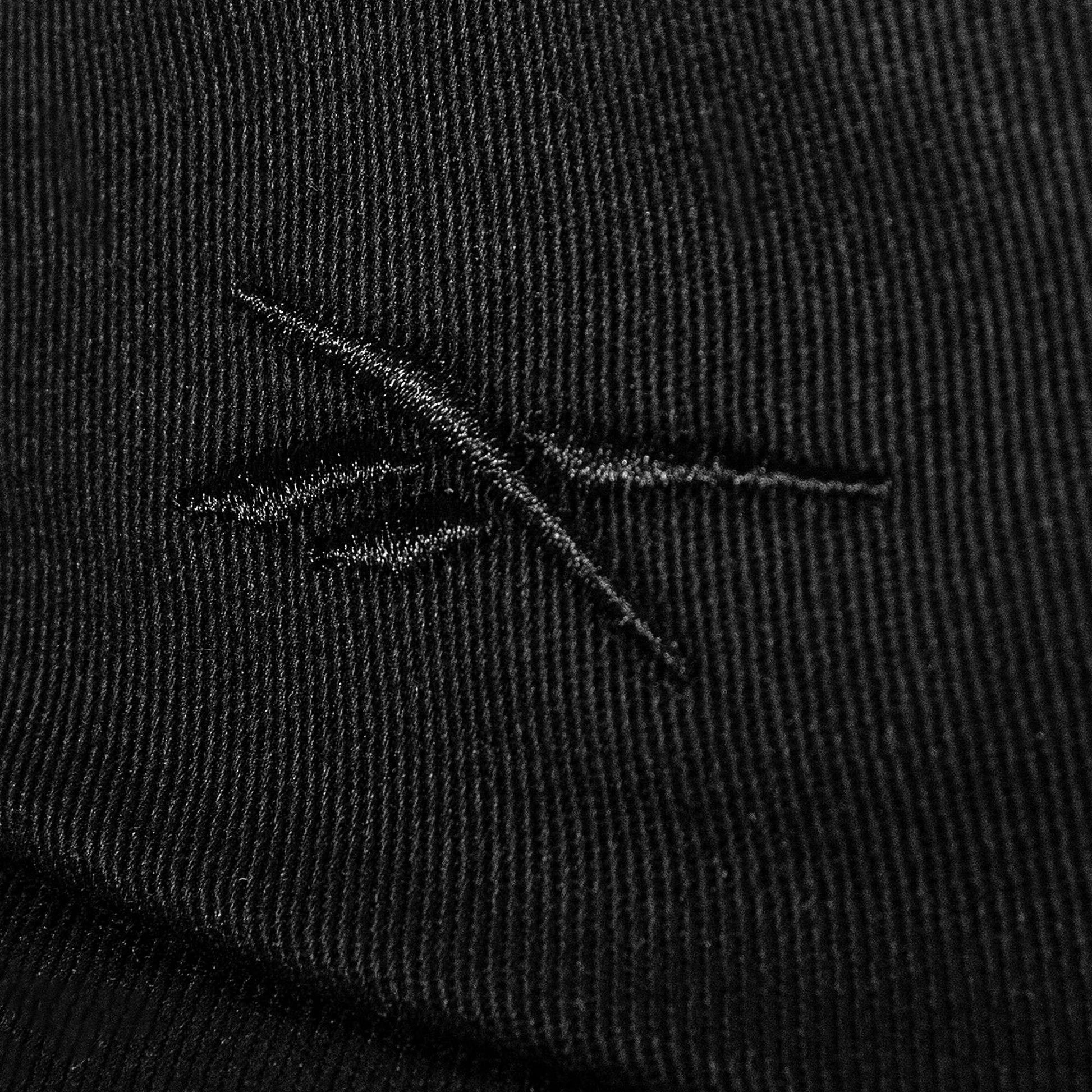Close-up of black cotton twill fabric on the Reebok Logo S-Vector Cap, featuring a stitched abstract crossed-lines logo and textured pattern on an adjustable snapback.