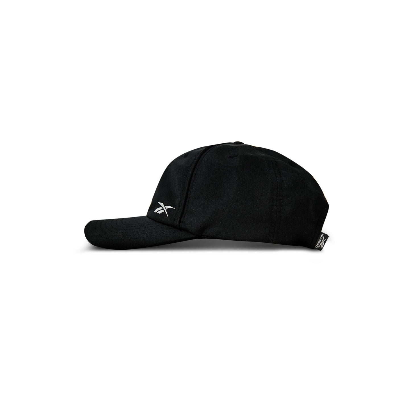 A black Reebok Flow Piped Cap made from recycled polyester, featuring a slightly curved brim and a small white Reebok logo on the front left side, is shown in profile against a white background.