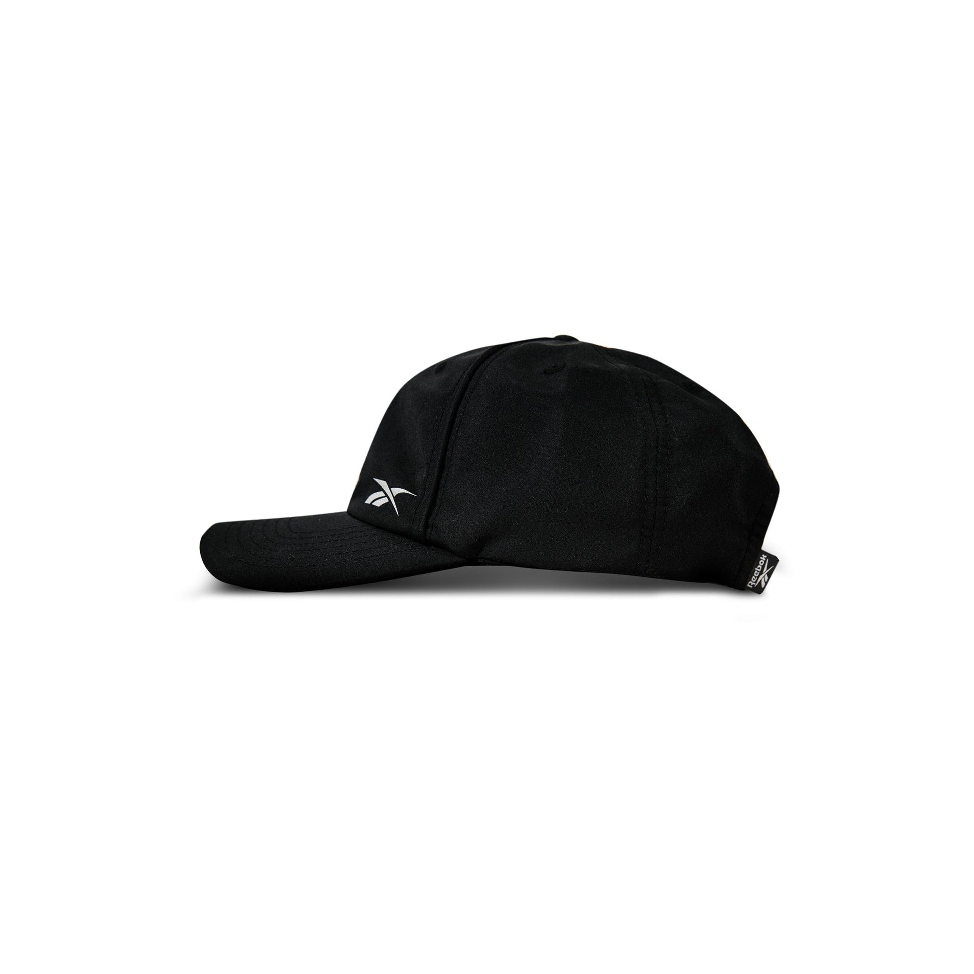 A black Reebok Flow Piped Cap made from recycled polyester, featuring a slightly curved brim and a small white Reebok logo on the front left side, is shown in profile against a white background.