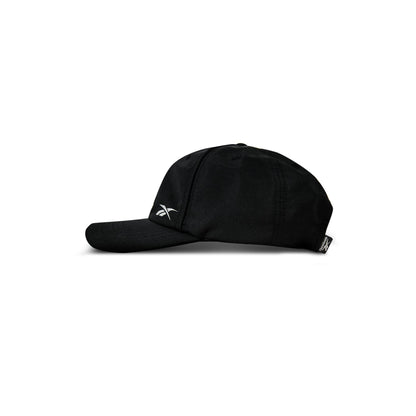 A black Reebok Flow Piped Cap made from recycled polyester, featuring a slightly curved brim and a small white Reebok logo on the front left side, is shown in profile against a white background.