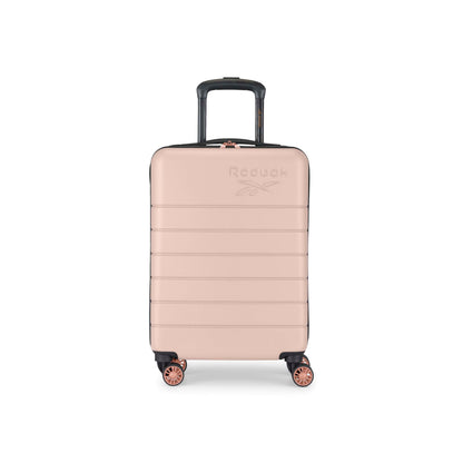 A rose gold hard-shell suitcase with four wheels and a black retractable handle, featuring the Reebok logo embossed on the front. The suitcase is photographed against a white background.