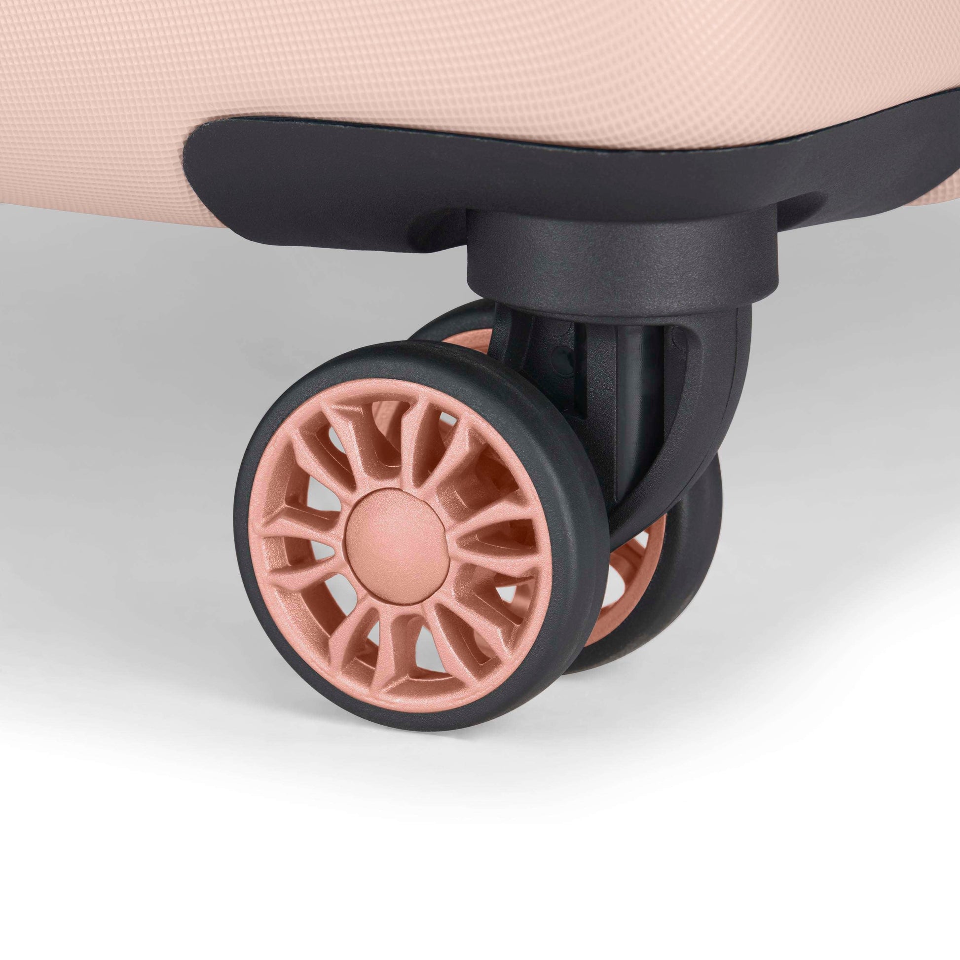 Close-up of a pink suitcase wheel with a black rim and spokes, attached to the bottom corner of the suitcase on a white background.