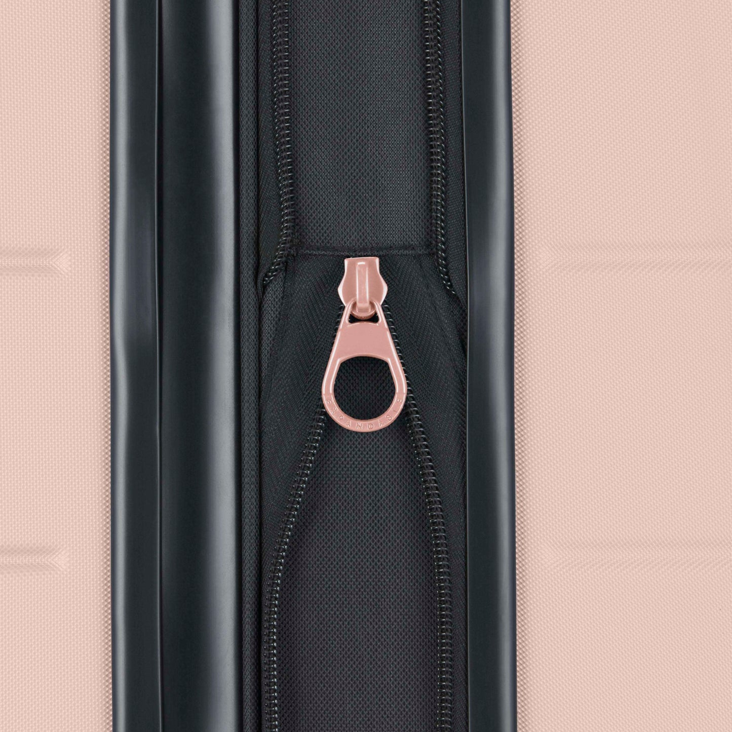 Close-up of a black zipper with a pink pull tab on a textured pink suitcase. The zipper is centered vertically between two suitcase panels.