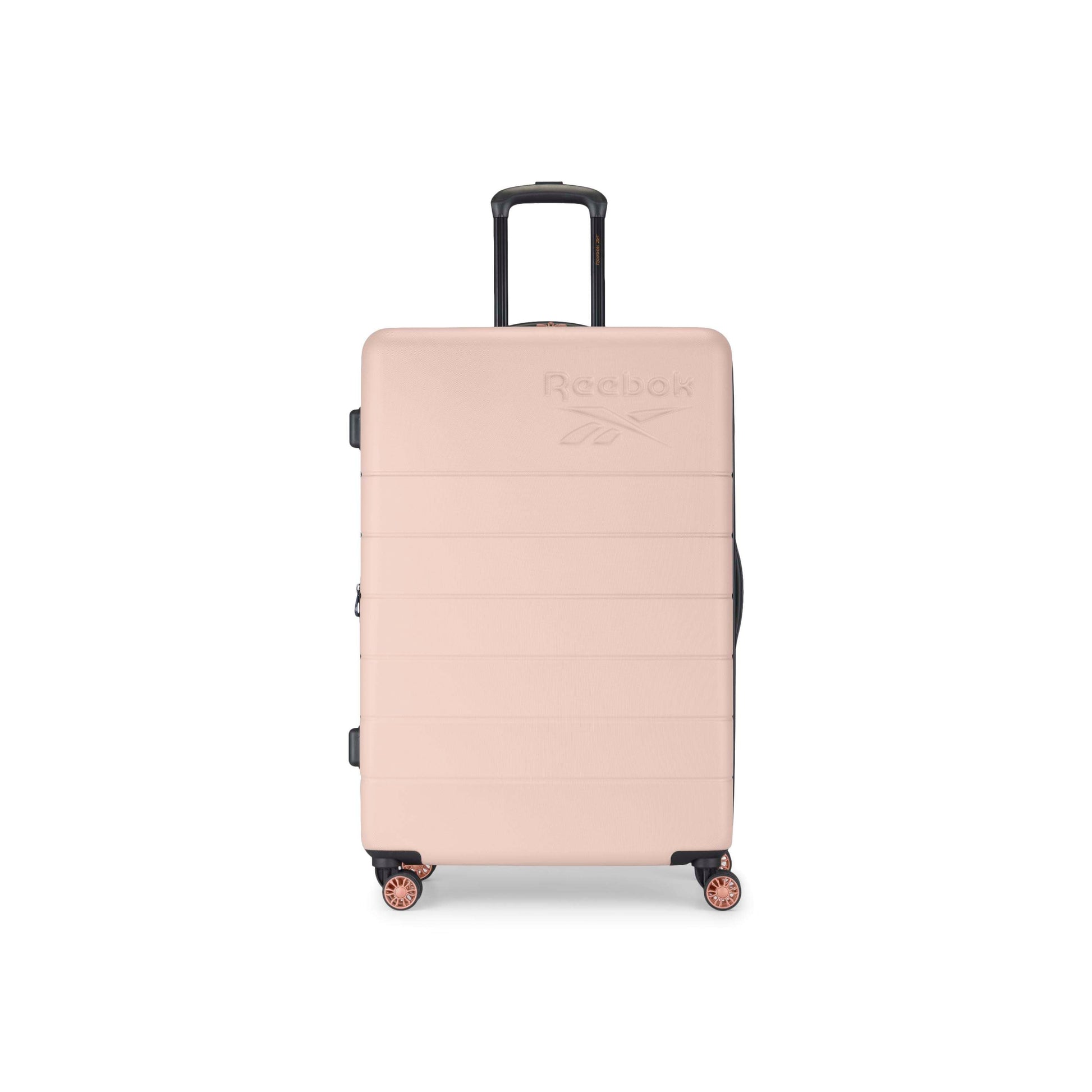 A large, light pink hard-shell suitcase with four wheels and a black telescopic handle. The Reebok logo is embossed on the front. The suitcase is standing upright against a plain white background.