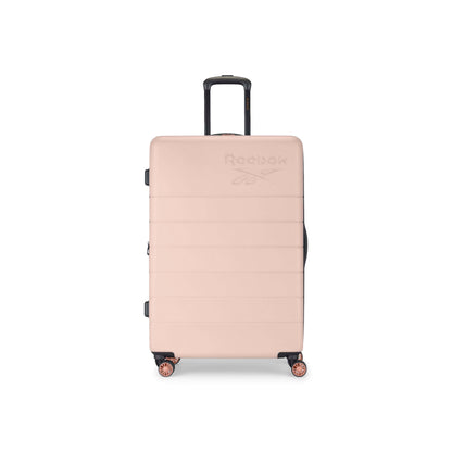 A large, light pink hard-shell suitcase with four wheels and a black telescopic handle. The Reebok logo is embossed on the front. The suitcase is standing upright against a plain white background.
