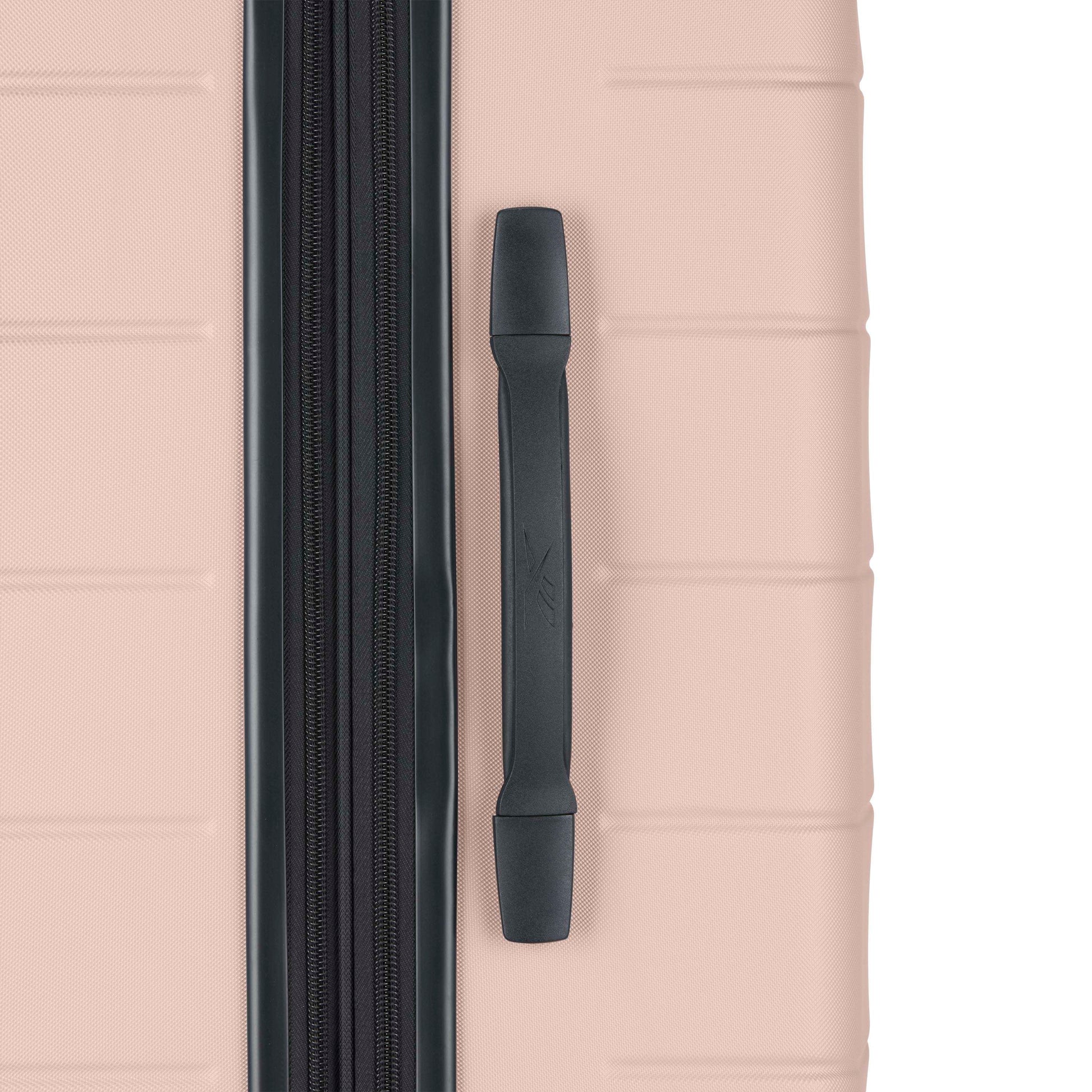 Close-up of a light pink hard-shell suitcase showing a vertical black zipper and a black handle on the right side. The suitcase surface has horizontal indented lines for texture.