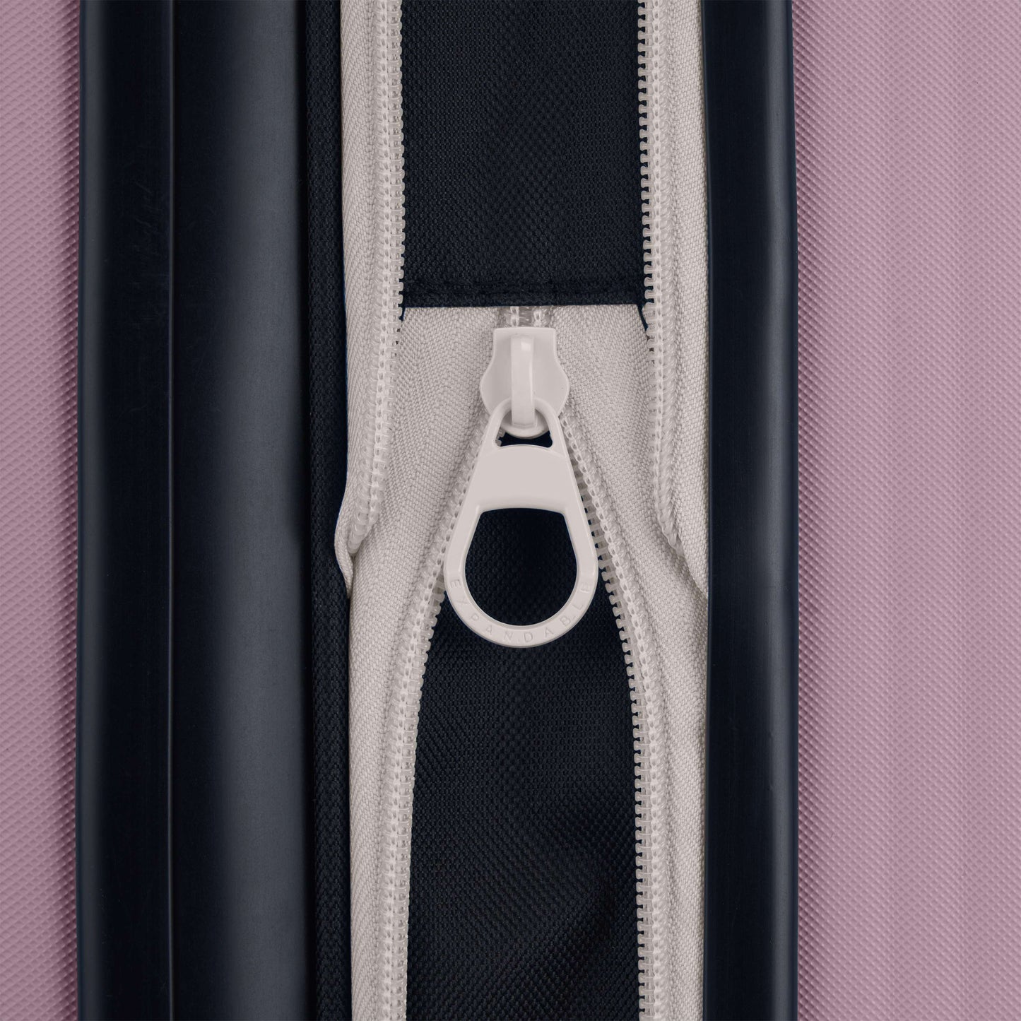 Close-up of a white zipper on black and gray fabric, bordered by black on the left and pink on the right—part of the stylish Reebok Action Duo 2 Piece Luggage Set.