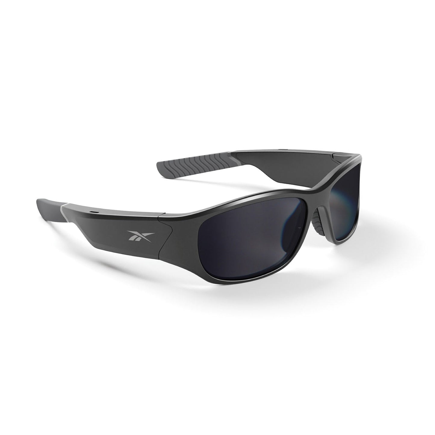 The Reebok Nitrous Smart Audio Sunglasses feature a black wraparound design, dark polarized lenses, and a side Reebok logo, displayed on a white background.