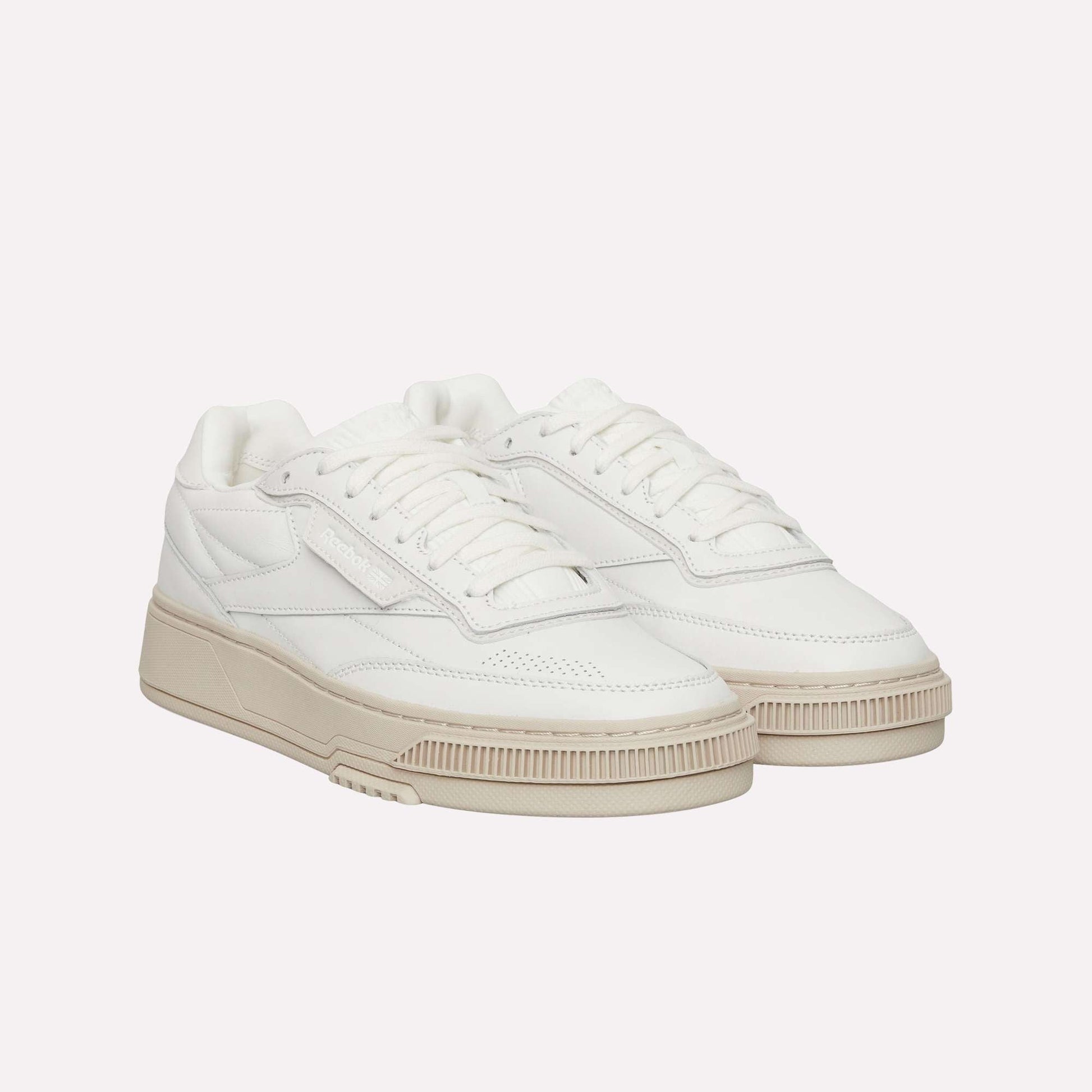 The Reebok Club C LTD Shoes feature a clean, minimalist white low-top design with beige chunky soles, white laces, and subtle stitching details—making them a timeless lifestyle classic.