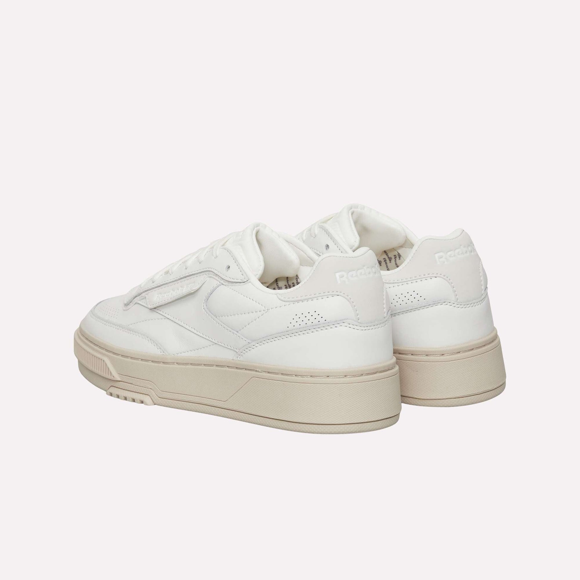 A pair of Reebok Club C LTD Shoes in white with beige soles, shown from the back and side, highlighting the brand logo and stitching on a clean white background—a timeless lifestyle classic.