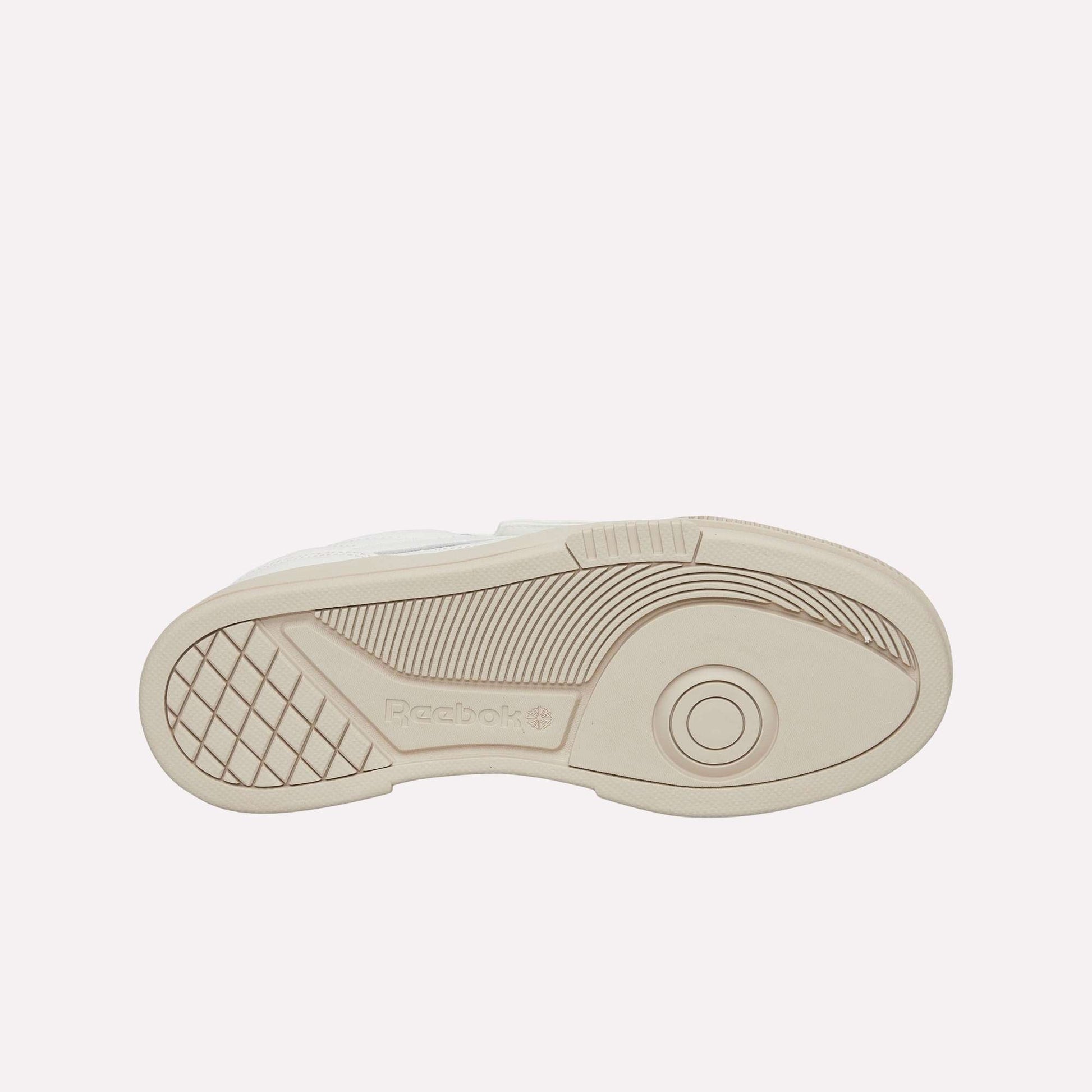 The image displays the beige rubber outsole of Reebok Club C LTD Shoes, featuring geometric tread patterns, the Reebok logo, and concentric circles near the toe for enhanced grip and traction.