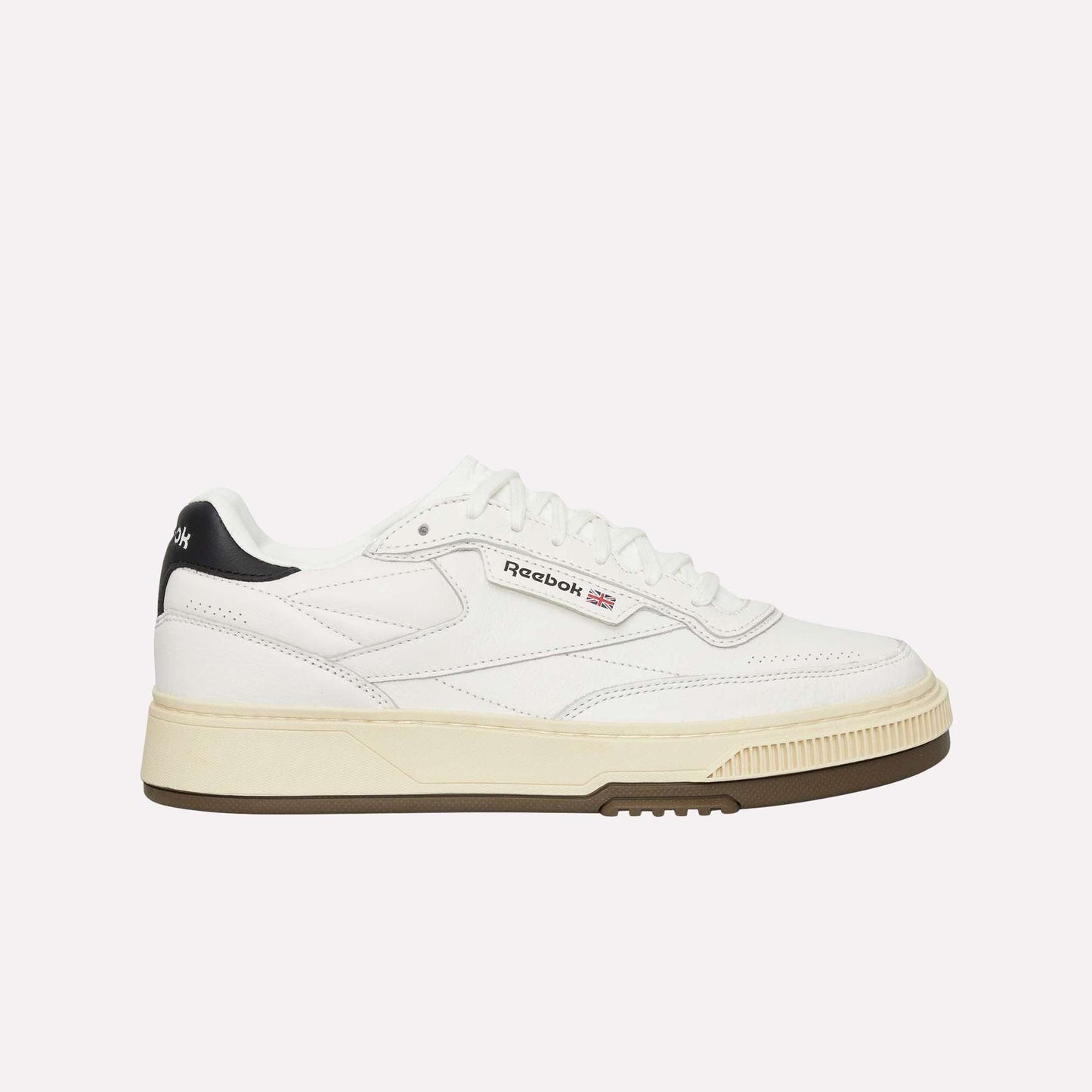 A white Reebok sneaker with a beige sole, black heel detail, and Reebok logo on the side, shown in a side profile on a plain white background.