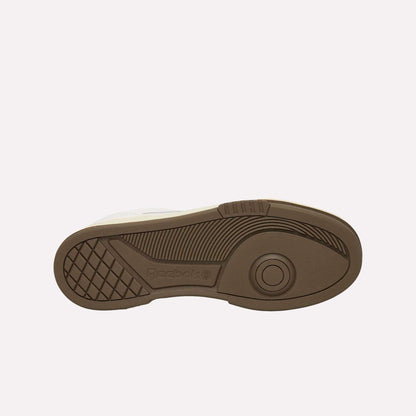 The image shows the brown rubber sole of a Reebok sneaker, viewed from the bottom, featuring textured grip patterns and the Reebok logo embossed near the heel. The sole is set against a plain white background.