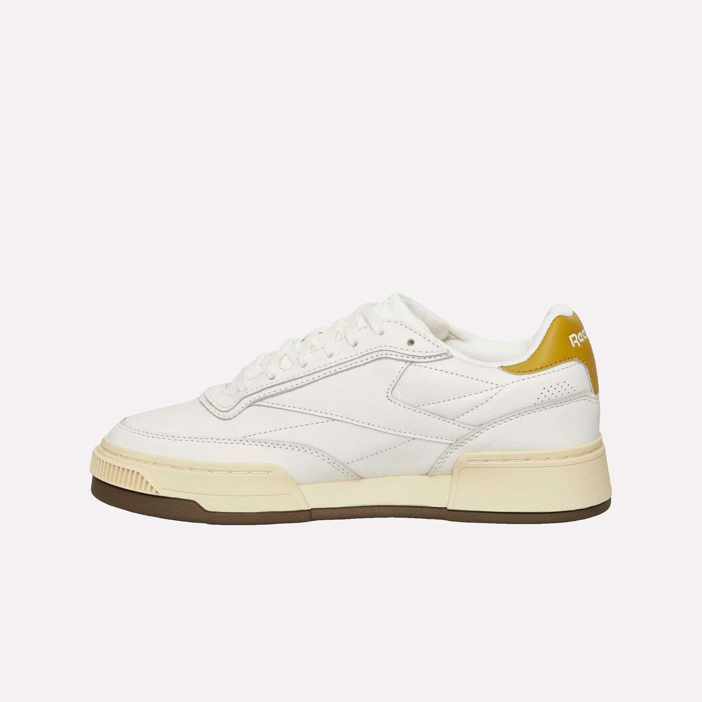 The Reebok Club C LTD Shoes, a white low-top with cream sole, light brown outsole, and yellow heel tab with the Reebok logo, are shown against a plain light blue background.