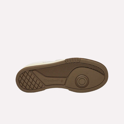 The image displays the brown rubber sole of the Reebok Club C LTD Shoes against a light blue background, featuring a circular pattern, textured lines, and visible Reebok branding on this lifestyle classic.
