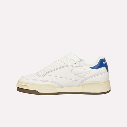 The Reebok Club C LTD Shoes feature white leather, a cream sole, brown outsole, blue heel accent, white laces, and minimalist Club C branding on the heel tab.